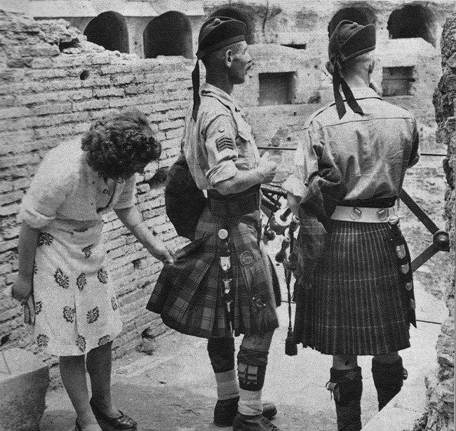 A curious Italian woman inspects the kilt of a Scottish soldier