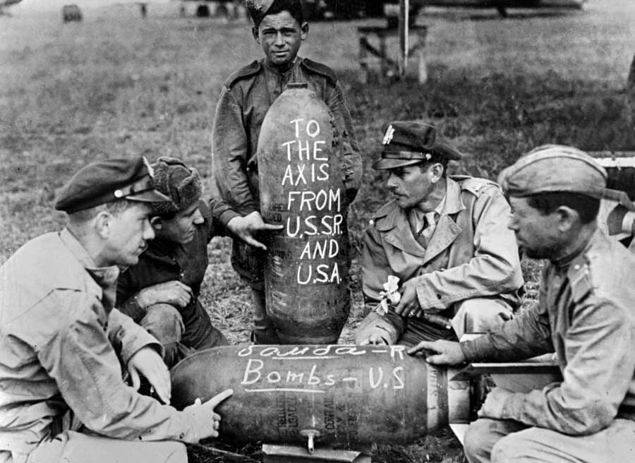 Soviet and American airmen pose with the bombs